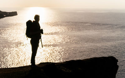 Silhouette man looking at sea against sky