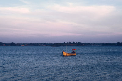 Boat sailing on sea against sky during sunset