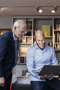 Happy businessmen using laptop together in office