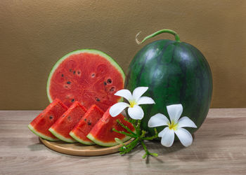 Close-up of watermelons and flowers on table