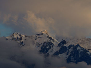 Scenic view of snow covered mountains against foggy sky