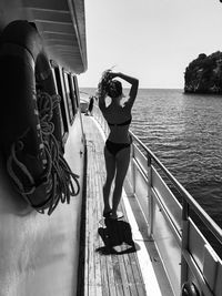 Sensuous young woman in bikini standing on boat deck