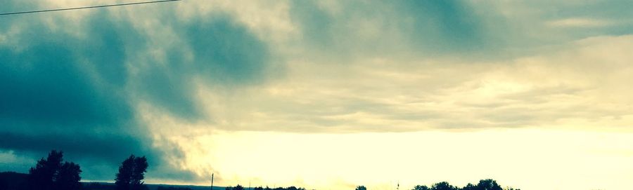 Silhouette of trees against cloudy sky