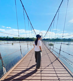 Rear view of woman standing on bridge against sky