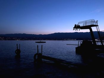 Silhouette pier on lake against clear sky at dusk