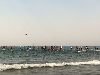 People participating in paddleboarding competition on sea