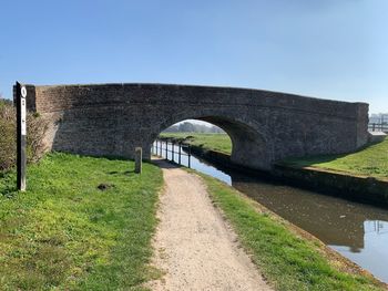 Arch bridge on field against sky