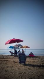 People at beach against clear sky
