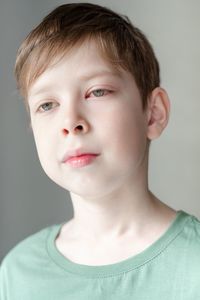 Portrait of a boy of european appearance with a red eye from conjunctivitis, on a white background