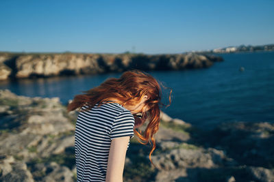 Woman standing on rock against sky