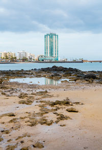 Sea by modern buildings against sky in city