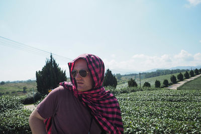 Portrait of young man wearing sunglasses on field against sky