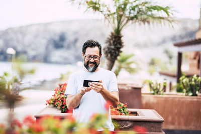 Man holding mobile phone outdoors