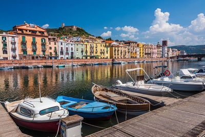 Boats moored at harbor by buildings in city