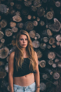 Portrait of woman standing against logs