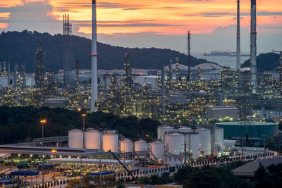 Illuminated factory against sky during sunset