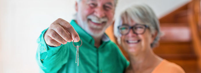Portrait of smiling senior couple holding house key at home