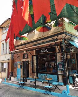 Chairs and tables at sidewalk cafe against buildings in city