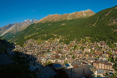 High angle view of townscape and mountains against blue sky