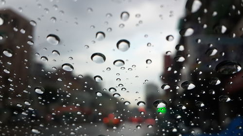 Close-up of wet window against sky