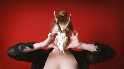 Mysterious occult woman holding animal deer skull in front of her face