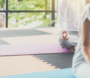 Low section of person meditating while sitting in yoga studio