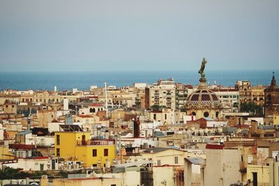 High angle view of townscape by sea against clear sky