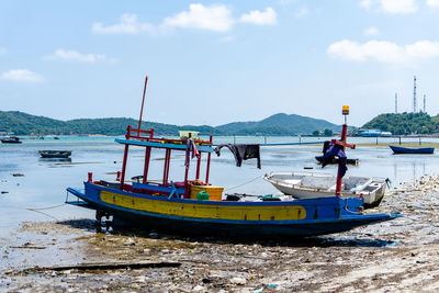 Fishing boats moored on sea against sky