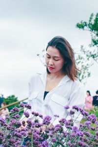 Beautiful woman with pink flower against sky