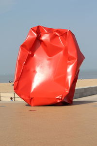 Close-up of red umbrella on beach against clear sky