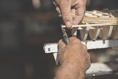 Close-up of man working on wooden boat model