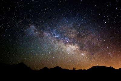 Scenic view of silhouette mountains against star field at night