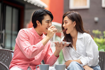 Smiling friends using mobile phone while sitting at home