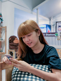 Young woman using mobile phone at home