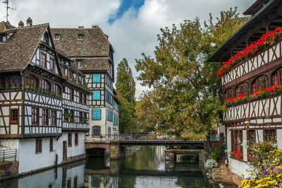 Buildings by canal against sky in city