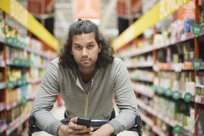 Man in supermarket holding cell phone and looking at camera