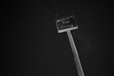 Low angle view of information sign against sky at night