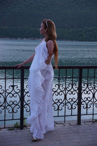 Woman standing by railing against sea