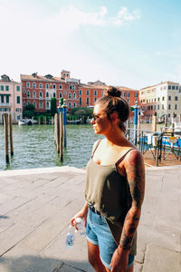 Full length of woman standing by canal in city