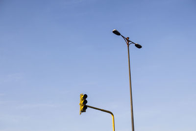 Low angle view of street light and road signal against clear sky