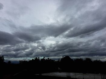 Silhouette of trees against cloudy sky