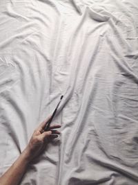 Cropped hand with paintbrush on bed