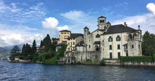 Buildings by river against sky