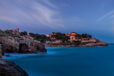 Buildings by sea against sky at night