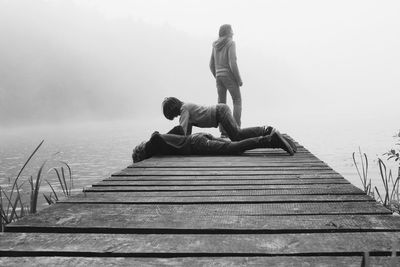 Mother with daughters on pier at lake during foggy weather