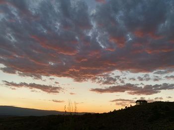 Silhouette landscape against dramatic sky during sunset