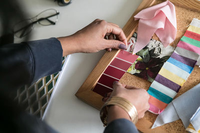 Cropped hands of businesswoman holding color swatches at desk in home office