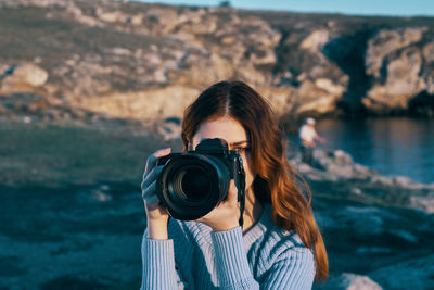 Portrait of young woman photographing sea