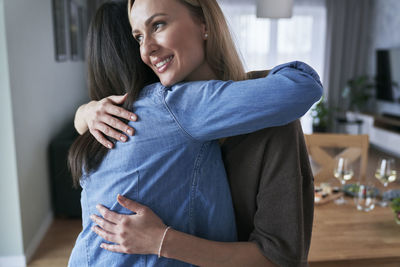 Female friends embracing at home