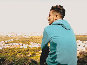 Rear view of young man looking away against clear sky